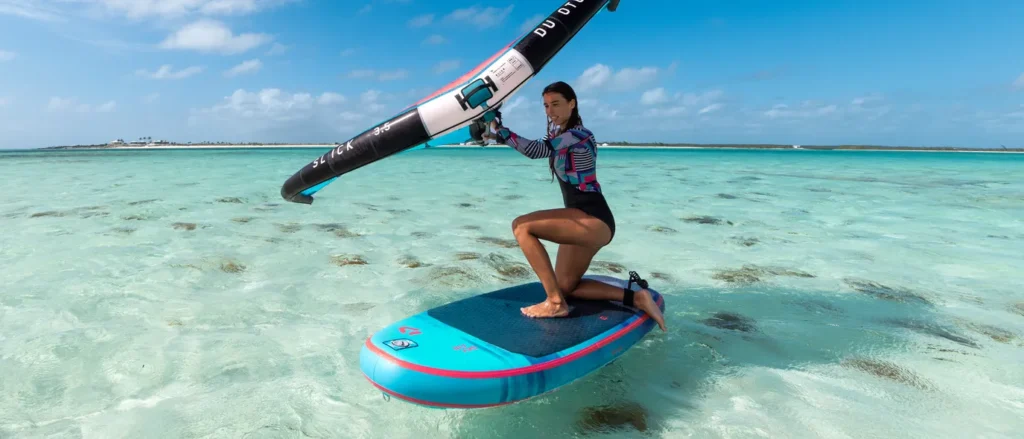 Wingfoiler maakt aanstalten om op haar foilboard te gaan staan.